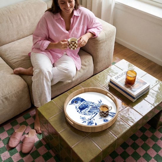 Rond houten dienblad met Delfts blauw vogeldecor, op een salontafel.