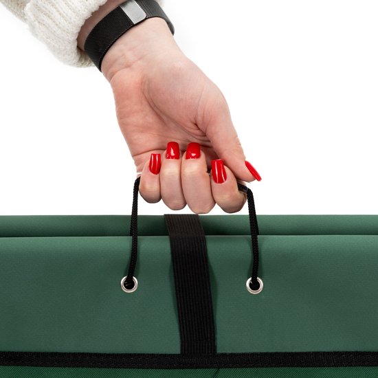 Hand met rode nagellak die de draaglus van de groene opvouwbare kruiwagen vasthoudt.