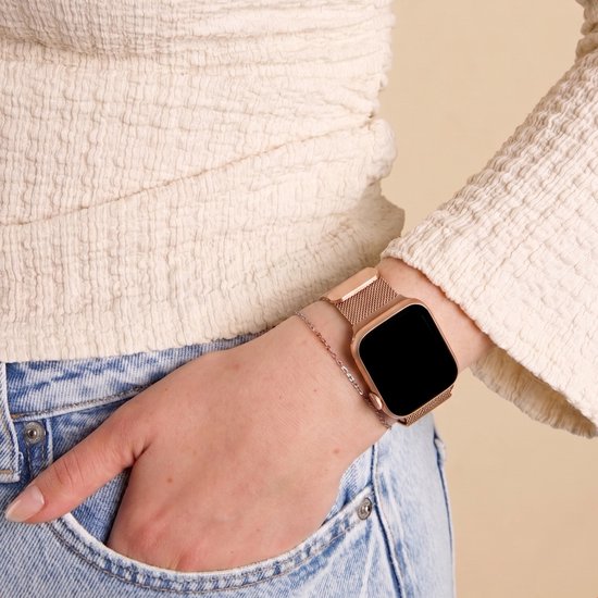 Rosegouden Milanese bandje om een pols met blauwe jeans en een crèmekleurig shirt. Met bijpassend armbandje.