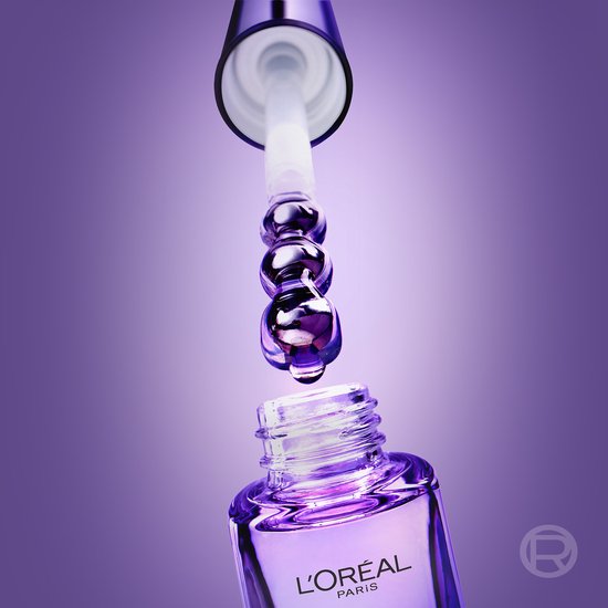 Paarse druppels van L'Oréal Paris oogserum vallen uit de applicator in het flesje op een paarse achtergrond.