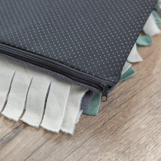 Donkergrijze achterkant van een snuffelmat met anti-slip noppen en rits. Rand met witte en lichtgroene stroken.