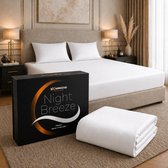 Een bed met witte lakens, een doos en een opgevouwen laken. "Night Breeze" logo zichtbaar.