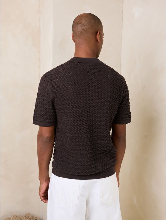 Achterkant van een man in een bruin poloshirt met visgraatpatroon.
