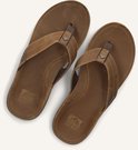 Bovenkant van een paar bruine leren Reef teenslippers met suède bandjes.