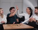Twee spelers van een magnetenspel geven elkaar een high-five, anderen kijken toe.