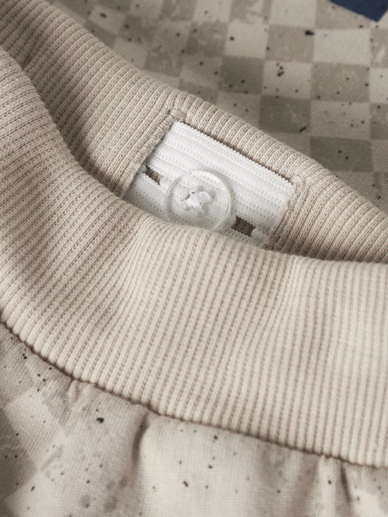 Detail van de tailleband van een beige joggingbroek met verstelbare knopen.