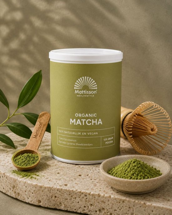 Mattisson biologische matcha poeder met blaadjes, lepel en whisk.