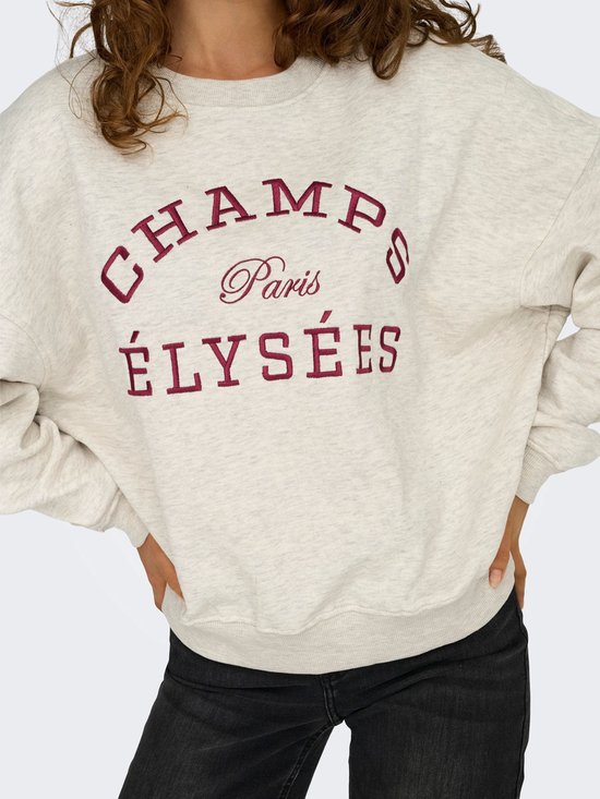 Close-up van een lichtgrijze sweater met geborduurde tekst 'CHAMPS Paris ÉLYSÉES' in donkerrood.