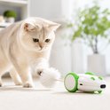 Een kat jaagt op een witte en groene robotmuis met een witte pluizige staart op de vloer.