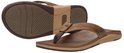 Twee bruine leren Reef teenslippers, de ene op zijn zool, de andere liggend.