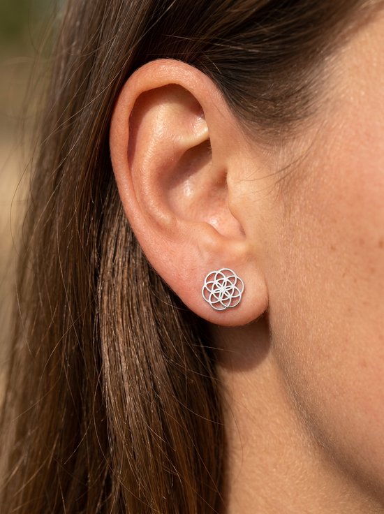 Bouton d'oreille argenté fleur de vie sur une oreille.