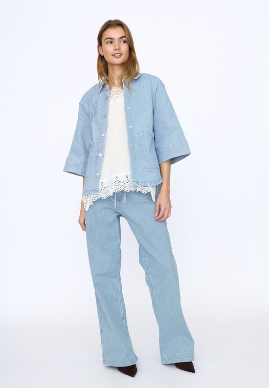 Model draagt een gestreept spijkerjack met bijpassende broek en wit kanten top.