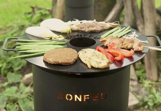 BonFeu tuinhaard met grillplaat, met erop gegrild vlees, groenten en een burger.
