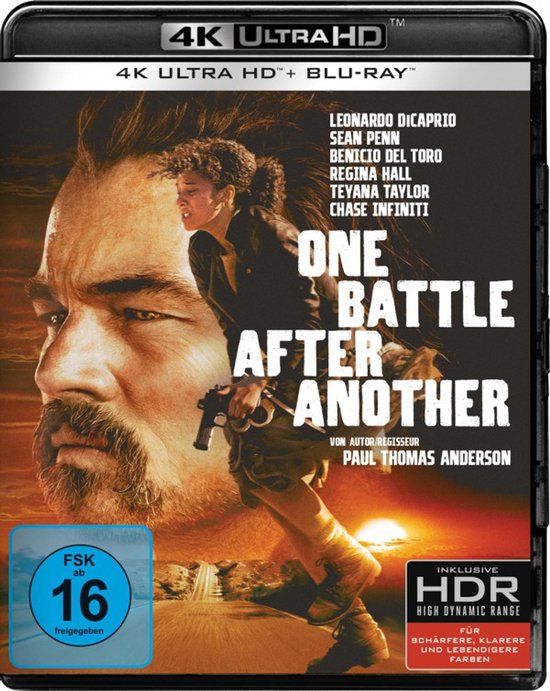 Hoes van "One Battle After Another" met Leonardo DiCaprio en vrouw met pistool. Zonsondergang en FSK 16 logo.