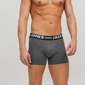 Grijze boxer met zwarte elastische band met witte tekst: JACK & JONES, gedragen door een man.