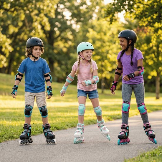 Drie kinderen in beschermende uitrusting rolschaatsen in een park, twee met roze en mintgroene skeelers.