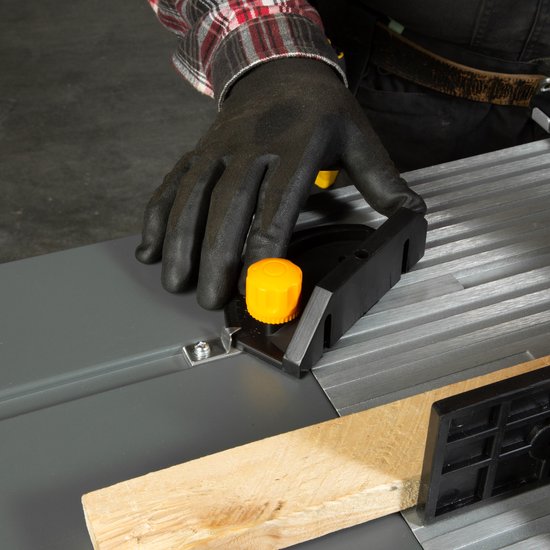 Hand in een zwarte werkhandschoen die een oranje draaiknop op de freestafel verstelt, met een stuk hout.