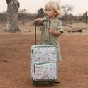 Jongetje met blonde haren in safari-kleding staat naast een koffer met safari print.