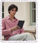 Man met roze gestreepte blouse leest zwarte BOOX Go e-reader buiten.