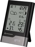 Zwarte Bresser weerstation met grijze basis, toont temperatuur, luchtvochtigheid, tijd en weersvoorspelling.