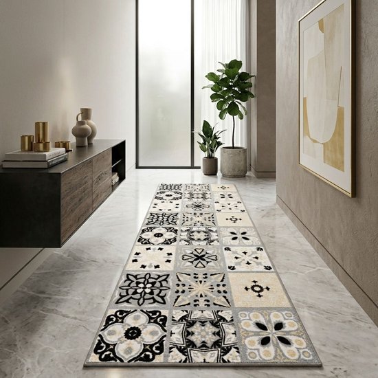 Un long tapis de couloir avec un motif de carreaux variés en gris, noir et crème, posé sur un sol en marbre dans un couloir.