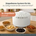 Witte Clatronic voedseldroger met vijf stapelbare niveaus, omringd door kommetjes met rozijnen, appelringen, pruimen en abrikozen.