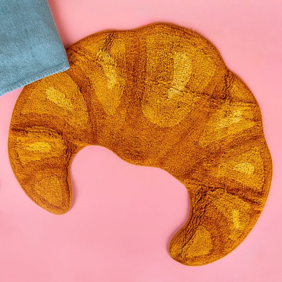 Un tapis de bain jaune moutarde en forme de croissant avec une serviette bleue à côté.