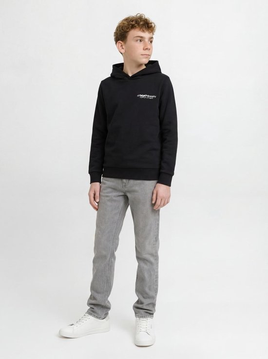 Jongen draagt zwarte hoodie met witte tekst en grijze jeans.
