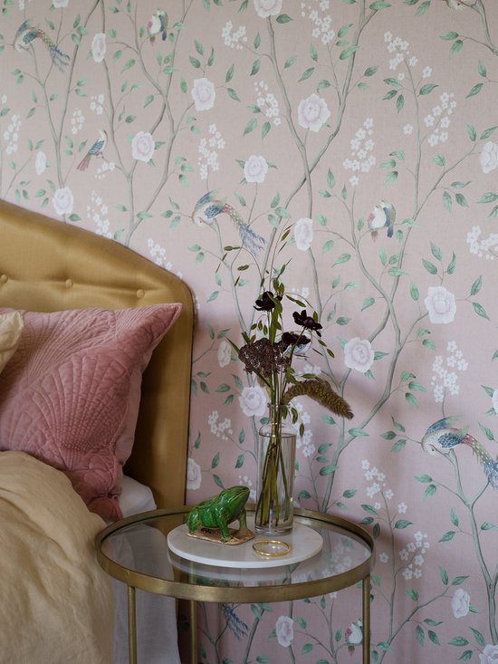 Roze bloemenbehang met vogels en een bijzettafel met bloemen en een kikker.