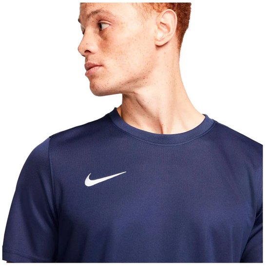 Man met kort rood haar, gezien van voren, draagt een marineblauw sportshirt met witte Nike swoosh.