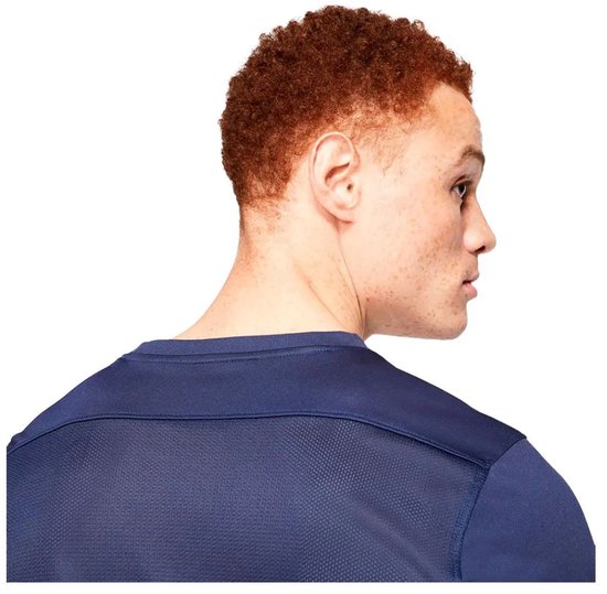 Model met rood haar, zijkant van het hoofd en donkerblauw Nike sportshirt, met detail op de schouder.