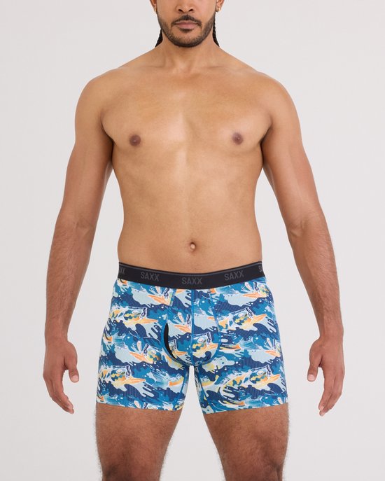Man met SAXX boxershort met blauwe, gele en oranje visprint. "SAXX" op de tailleband.