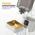 De voerautomaat wordt schoongemaakt met water. De gouden voerbak wordt apart gehouden.