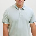 Close-up van een lichtblauwe poloshirt met een fijne textuur. De kraag heeft groene en witte strepen.
