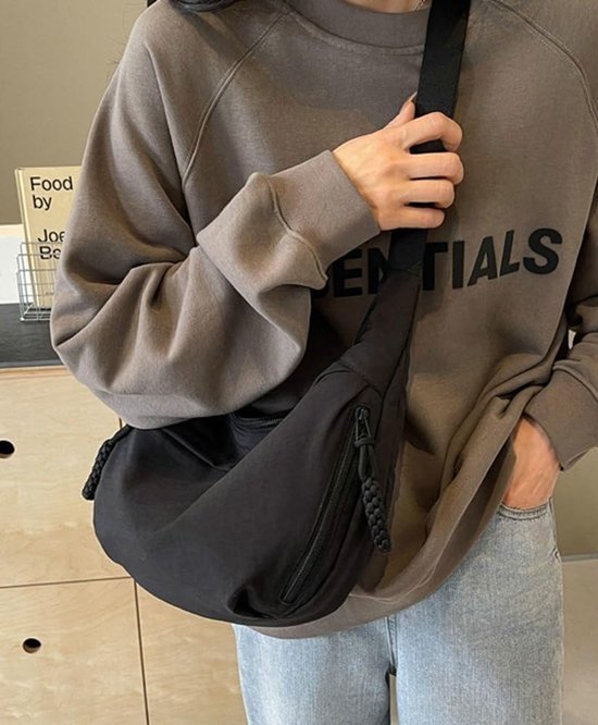 Zwarte crossbody tas met verstelbare band en gedraaide ritstrekker.