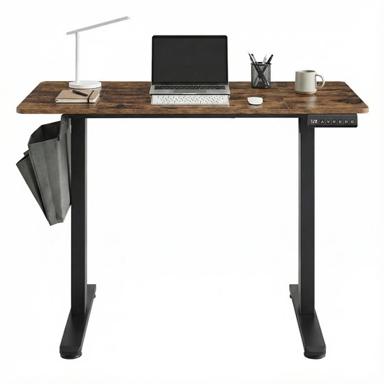 Bureau électrique assis-debout avec plateau aspect bois brun et cadre en métal noir. Bureau avec ordinateur portable, clavier, souris, carnet, stylo, lampe et tasse. Avec pochette de rangement grise sur le côté.