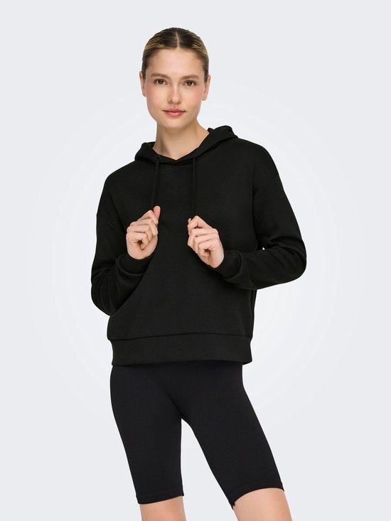 Model draagt een zwarte cropped hoodie.