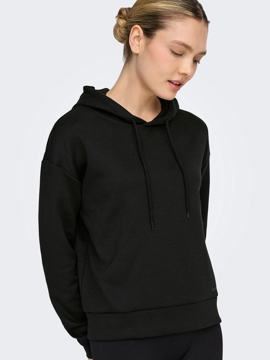Model draagt een zwarte cropped hoodie.