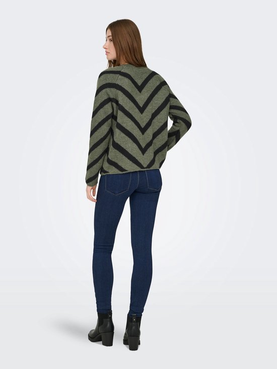 Model van achteren gezien in een olijfgroene trui met zwarte V-strepen en een spijkerbroek.