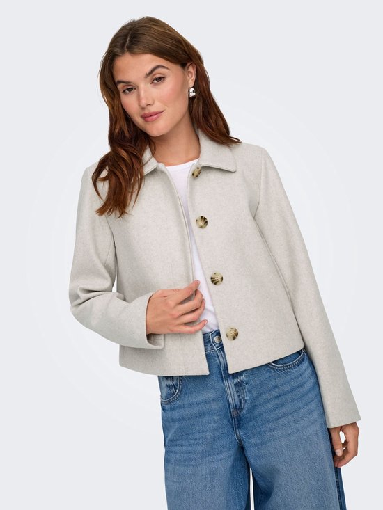 Model draagt een lichtgrijze korte jas van ONLY met jeans. De jas heeft knopen.