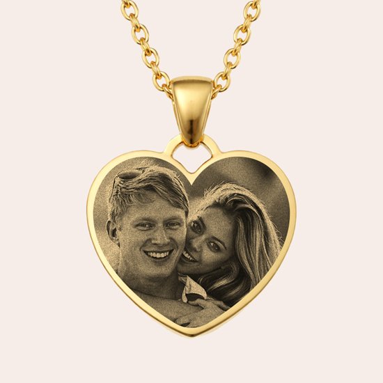 Pendentif cœur doré gravé d'un couple souriant, la femme appuyée sur l'épaule de l'homme.