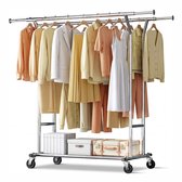 Verchroomd dubbel kledingrek op wielen met kleding in pastelkleuren, dozen en een koffer. Inclusief een witte jurk.