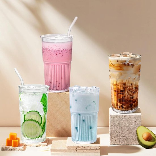Vier glazen bekers met verschillende dranken: groene met komkommer, roze, blauwe en ijskoffie. Geplaatst op stenen blokken.
