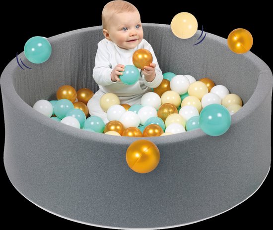 Een baby zit in een grijs ballenbad en houdt een gouden bal vast. Witte, gele en turquoise ballen zweven om het bad heen, met bewegingslijnen.