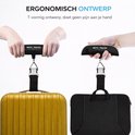 Twee handen gebruiken de zwarte bagageweegschaal om een gouden koffer en een zwarte laptoptas te wegen.