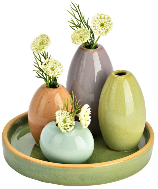 Vijf pastelkleurige, aardewerk mini-vazen met witte bloemen op een groen plateau.