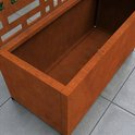 Close-up van de roestkleurige plantenbak op wieltjes met een geometrisch tuinscherm.