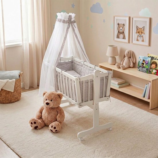 Witte wieg in een kinderkamer met een teddybeer, een hemel en afbeeldingen van dieren aan de muur.