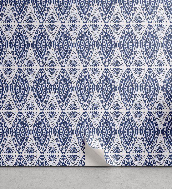 Behang met een repetitief patroon van blauwe ornamenten op een witte achtergrond. De onderkant van het behang krult los.