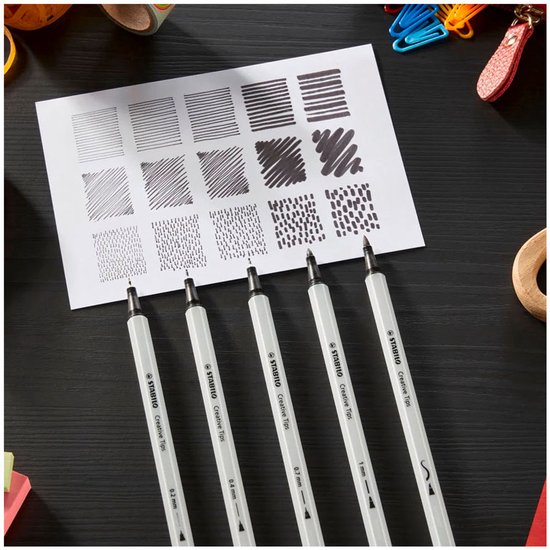 Vijf STABILO Creative Tips pennen met diverse puntdiktes (0.2 mm tot 1 mm) naast een vel papier met lijnen en stippen.